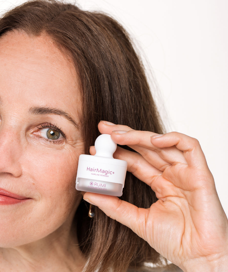 Woman over 50 holding the Hairline Powder + 4-in-1 Brush compact beside her hairline