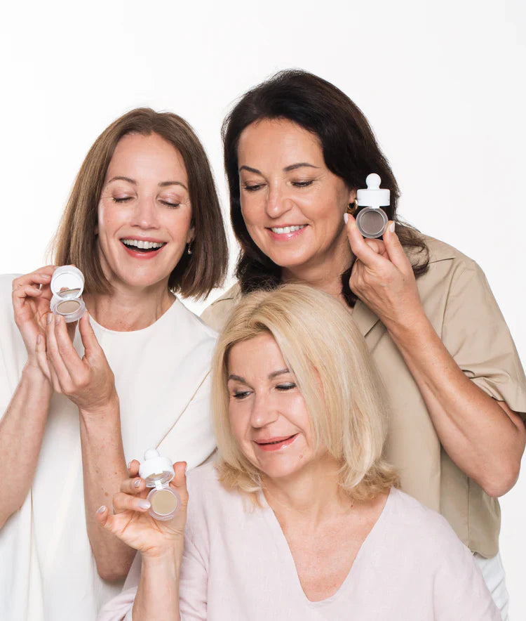 Three smiling women holding HairMagic+ powder for thinning hair and grey coverage