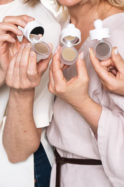 Women holding open HairMagic+ powder compacts for thinning hair and grey root coverage