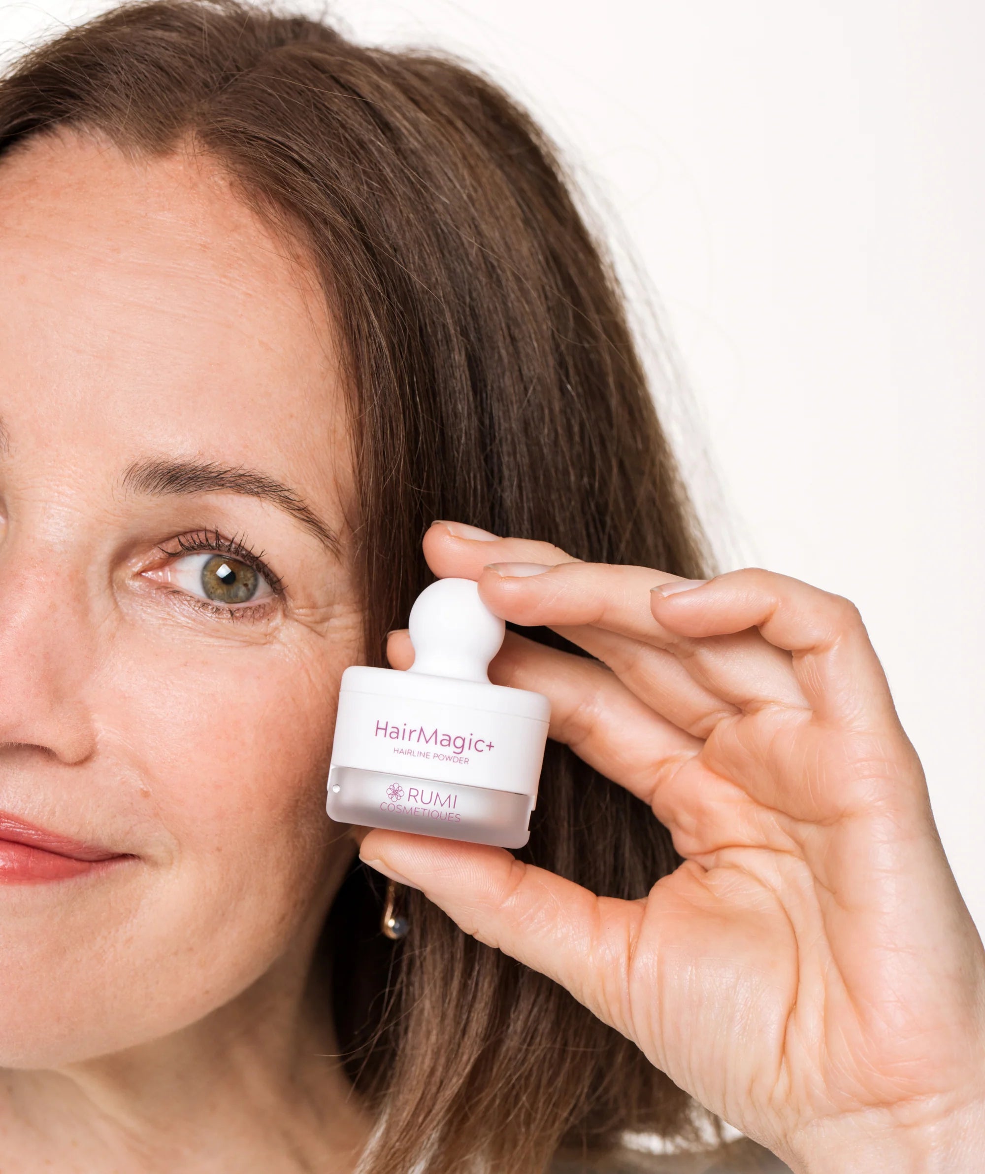 Smiling woman holding HairMagic+ powder for easy touch-ups and lasting coverage